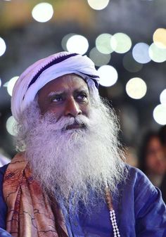 an old man with a long white beard wearing a purple turban and pearl necklace