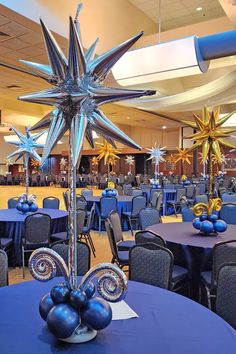 a large room filled with tables and chairs covered in blue table cloths topped with star decorations