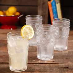 four glasses on a table with lemons in the background