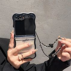 a woman holding up her cell phone to show it's chain and ring holder