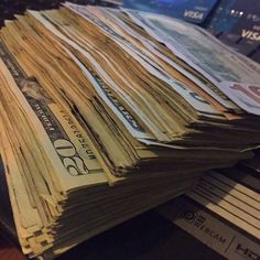 several stacks of money sitting on top of a laptop computer keyboard next to a pile of cash