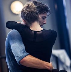 a man and woman hugging each other in the middle of a dance studio, black and white photograph