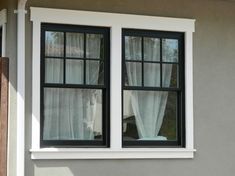 a cat sitting in the window sill of a house with curtains on it's windowsill