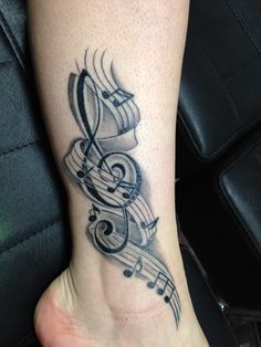 a tattoo with musical notes on it's foot and an ink pen in the shape of a treble