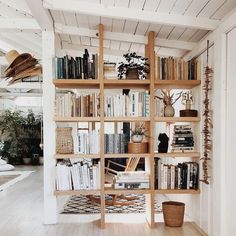 a bookshelf filled with lots of books next to a basket and potted plant