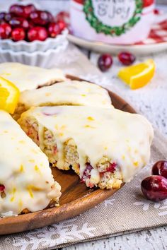 a wooden plate topped with cake covered in icing and cranberry toppings