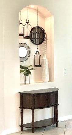 an entryway with a table, mirror and vases on the wall above it