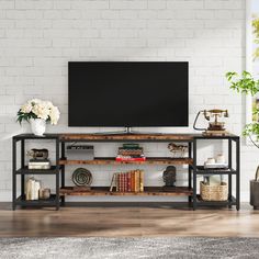 an entertainment center with books, vases and flowers on the shelves in front of a white brick wall