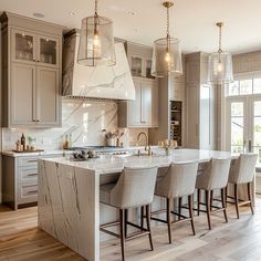 a large kitchen with marble counter tops and bar stools next to an island in the middle