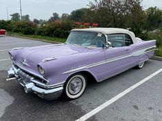 an old purple car parked in a parking lot