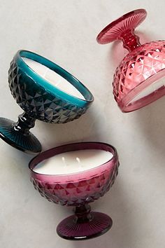 three glass candles sitting next to each other on a white counter top in front of a candle holder