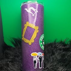 a purple starbucks cup sitting on top of a black fur covered floor next to a green wall