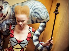 a woman with red hair standing next to two statues of cats and an elephant on display