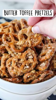 a hand is picking up some pretzels from a bowl