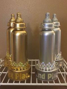 two silver and gold baby bottles sitting on top of a shelf