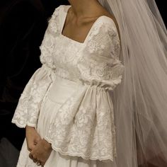 a woman in a wedding dress and veil standing next to a man wearing a suit