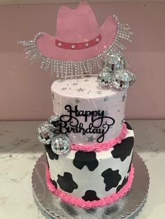 a birthday cake decorated with cow print and pink frosting is sitting on a silver platter