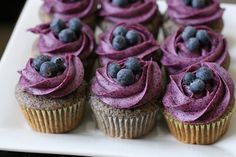 cupcakes with purple frosting and blueberries on top sit on a plate