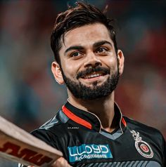 a man with a beard holding a bat in his hand and smiling at the camera