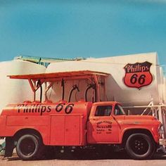 an orange truck parked in front of a gas station with phillips's 66 on the side