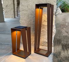 two modern outdoor lighting fixtures on the side of a building