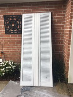 two white doors sitting next to a brick wall