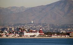 a city with mountains in the background and blue water on the foreground is a large body of water