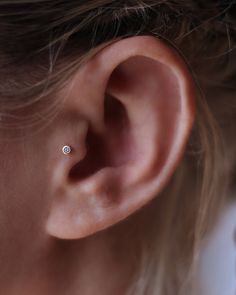 a woman's ear with a single diamond in the middle