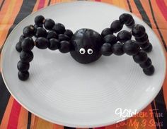 a spider made out of black beads on a white plate