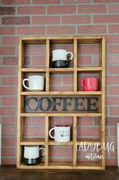 a wooden shelf with cups and mugs on it, against a red brick wall