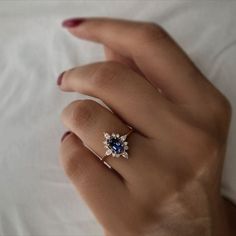 a woman's hand with a blue and white diamond ring on her left hand