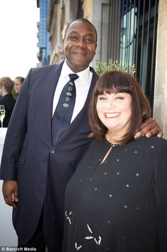 a man and woman standing next to each other in front of a building on a city street