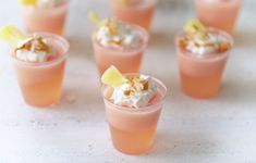 small glasses filled with different types of desserts on a white counter top, one has a lemon wedge and the other is topped with whipped cream