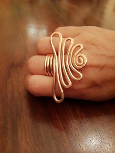 a person's hand with a gold ring on top of a wooden table,