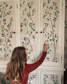 a woman is painting the wall with flowers on it