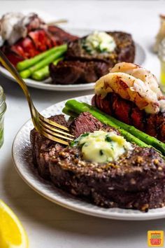 two plates with steak and asparagus on them, one has a fork in it