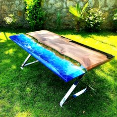 a wooden table sitting on top of a green grass covered field next to a stone wall