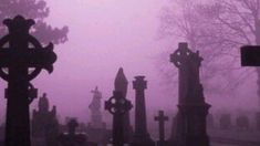 an old cemetery with tombstones and crosses in the fog