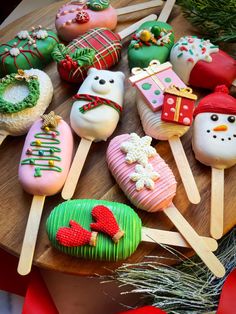 a wooden table topped with lots of decorated cookies and marshmallows covered in icing