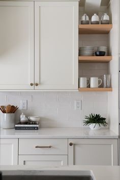 a kitchen with white cabinets and wooden shelves