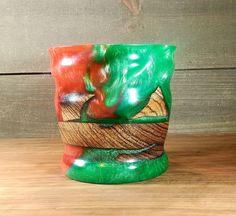 a green and red vase sitting on top of a wooden table