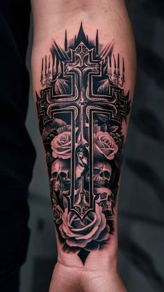 a man's arm with a cross, roses and candles tattoo on the forearm