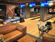 a bowling alley with couches, tables and televisions