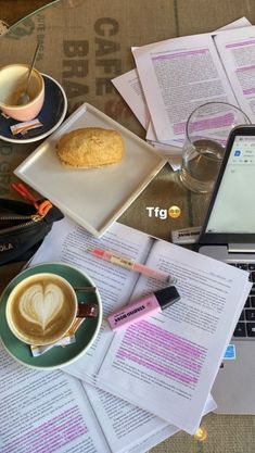 a laptop computer sitting on top of a table next to papers and coffee cup filled with liquid