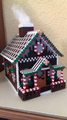 a house made out of legos sitting on top of a table next to a wall