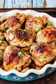 chicken with herbs in a blue and white dish on a wooden table top, ready to be eaten