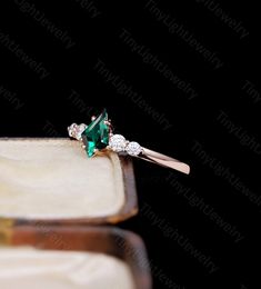 an emerald and diamond ring sitting on top of a box