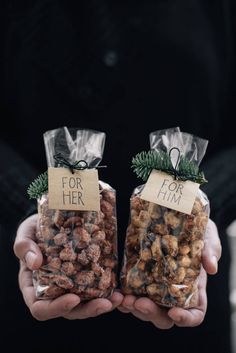 two hands holding bags of nuts with tags on them that say for her and for him