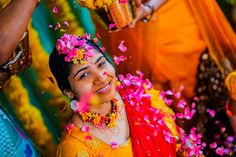 a woman is throwing flowers in the air and smiling at the camera while others look on