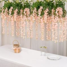 pink flowers hanging from the ceiling above a white table